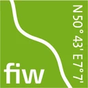 Eine Wissenschaftlerin und ein Wissenschaftler arbeiten hinter einer Glasfassade und mischen Chemikalien mit Großgeräten.